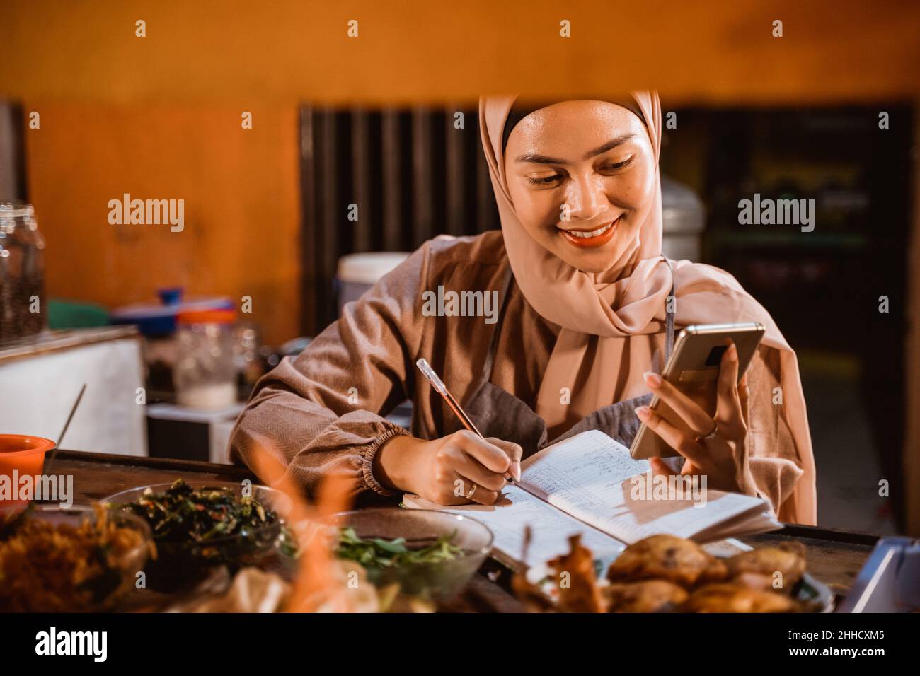 eine muslimische Frau schreibt einen Bericht über ihr Lebensmittelgeschäft Stockfoto