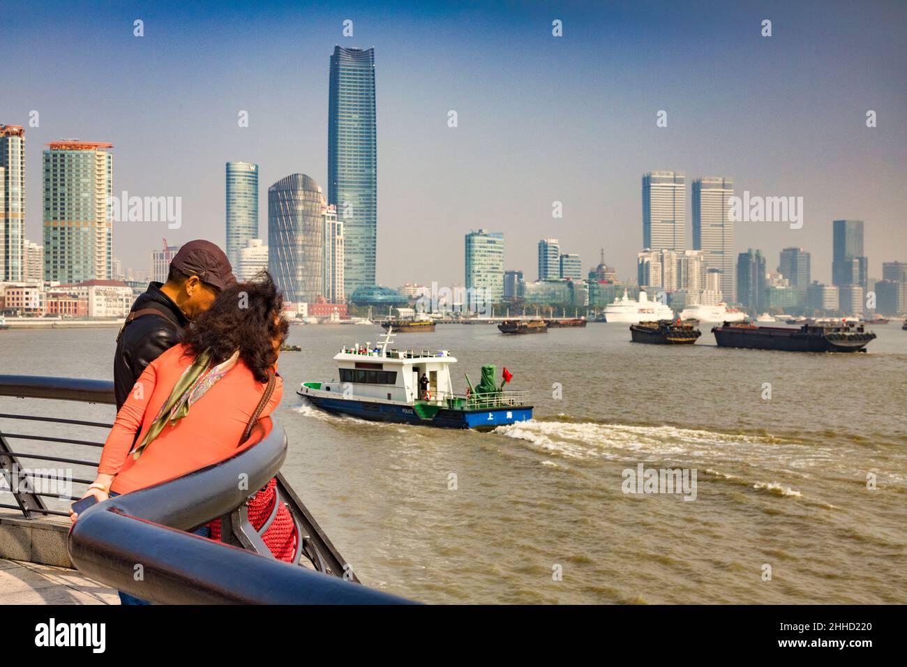 29. November 2018: Shanghai, China - das Touristenpaar lehnt sich an die Schiene und blickt auf die geschäftige Schifffahrt auf dem Huangpu-Fluss mit der Pudong Distri Stockfoto