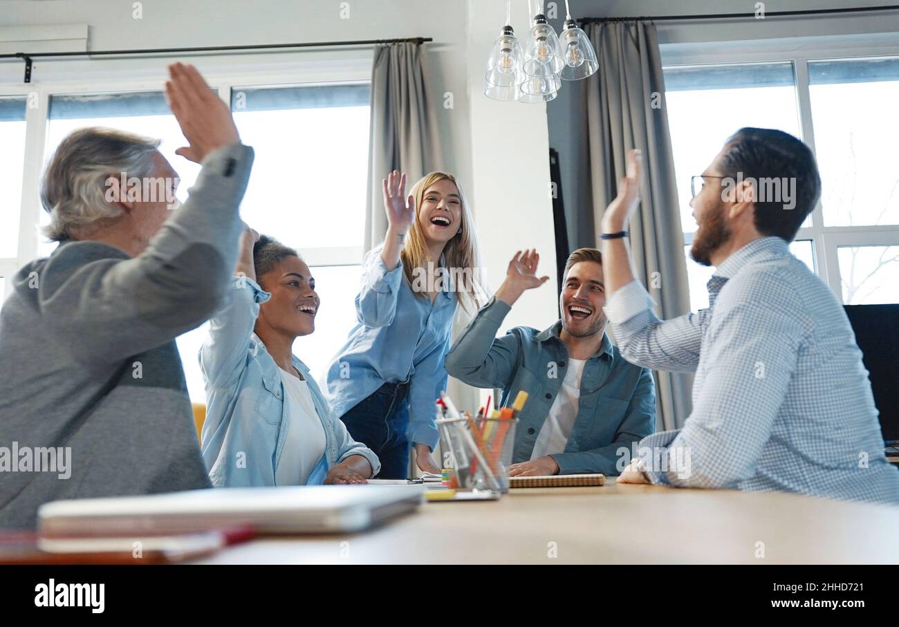 Begeistert motivierte, vielfältige Geschäftsleute geben hohe fünf zeigen Einigkeit und Unterstützung bei der Unternehmenssitzung, überglücklich multirassische Mitarbeiter engagiert in teambuil Stockfoto