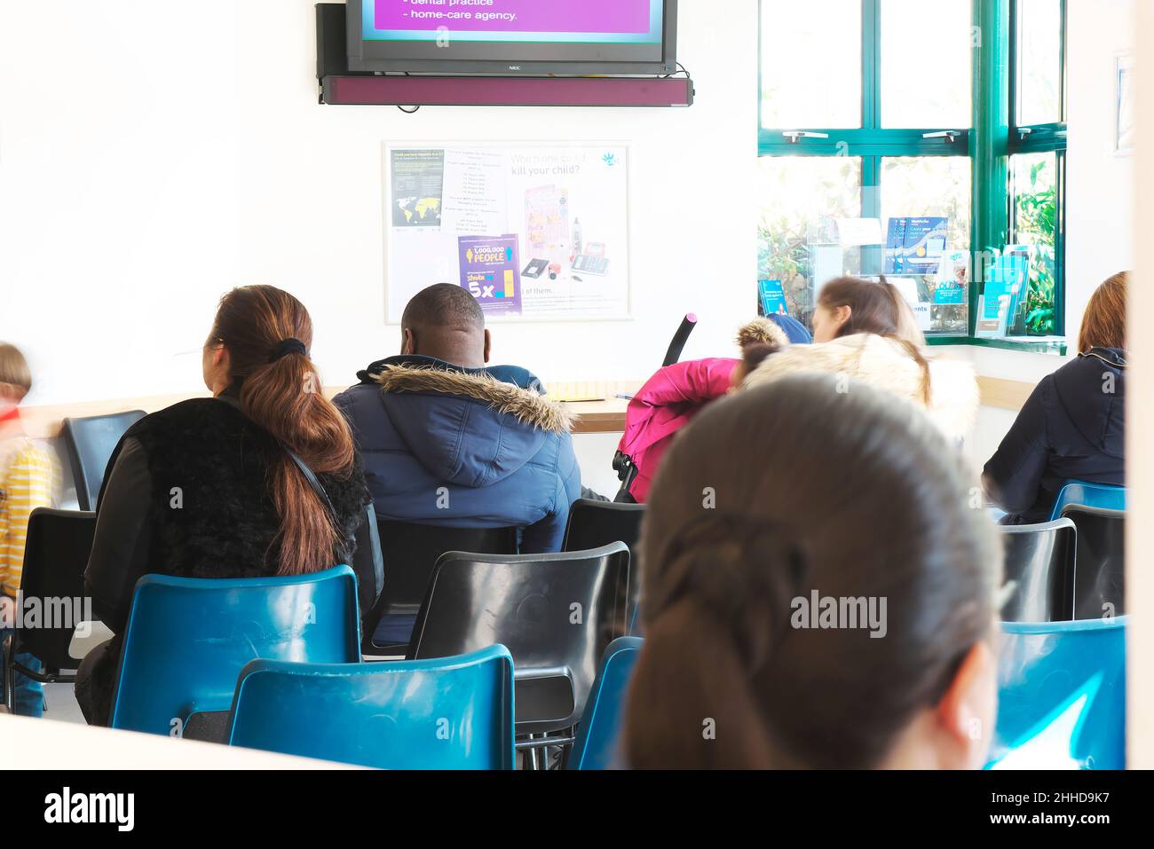 Verschiedene Menschen, die in einem OP-Wartezimmer eines Arztes sitzen und darauf warten, von einem Arzt oder einer Krankenschwester in einer geschäftigen Situation gesehen zu werden Stockfoto