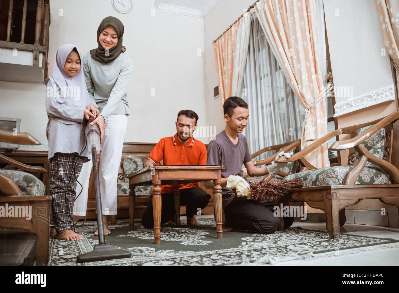 Vater, Mutter und zwei Kinder putzen gemeinsam das Familienzimmer Stockfoto