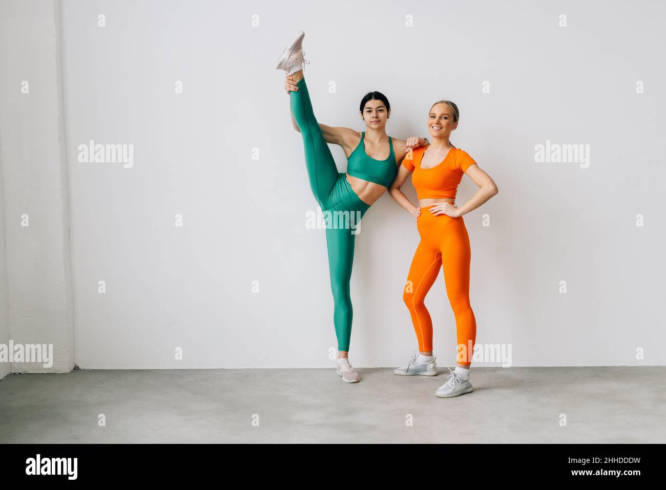 Zwei sportliche Frauen, die mit einem Stretchband auf dem Boden liegen, beim seitlichen Beinheben trainieren Stockfoto