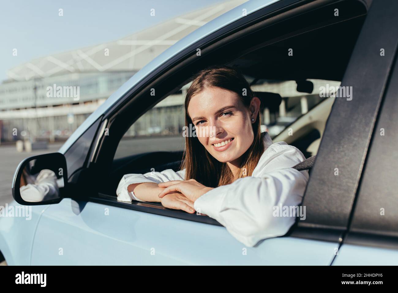 Porträt einer erfolgreichen Frau, die ein Auto fährt, fröhlich lächelt und die Kamera anschaut Stockfoto