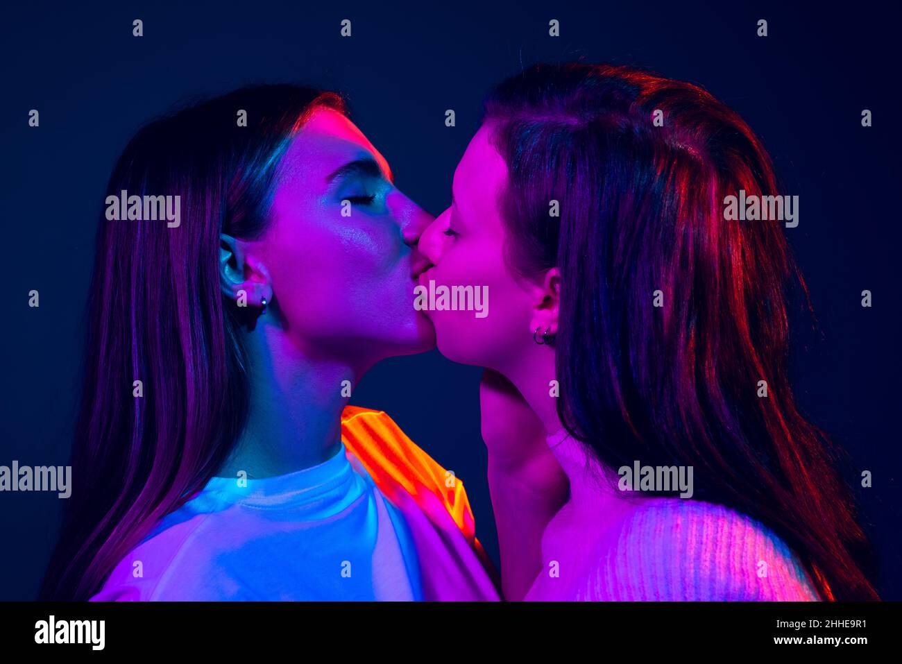 Nahaufnahme junge Mädchen, Paar isoliert auf blauem Hintergrund in Neonlicht. Konzept der Emotionen, Liebe, Beziehungen, romantische Ferien. Stockfoto