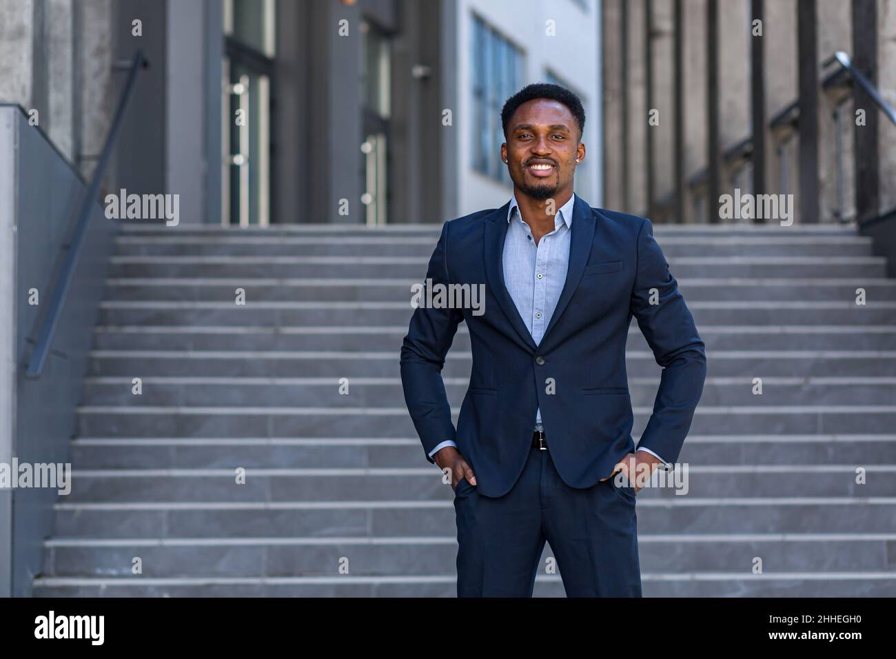 Erfolgreicher glücklicher Geschäftsmann vor dem Büro posiert und schaut Kamera afroamerikanischen Mann in Business Anzug lächelnd Stockfoto