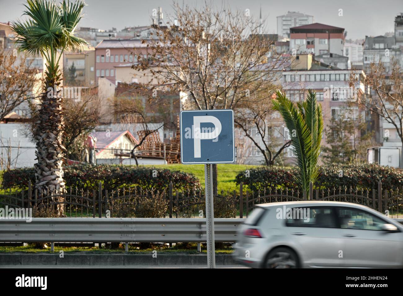 Selektiver Fokus Foto, Parkplatz Zeichen auf blauem Boden und verschwommen und Bewegung eines Autos. Stockfoto