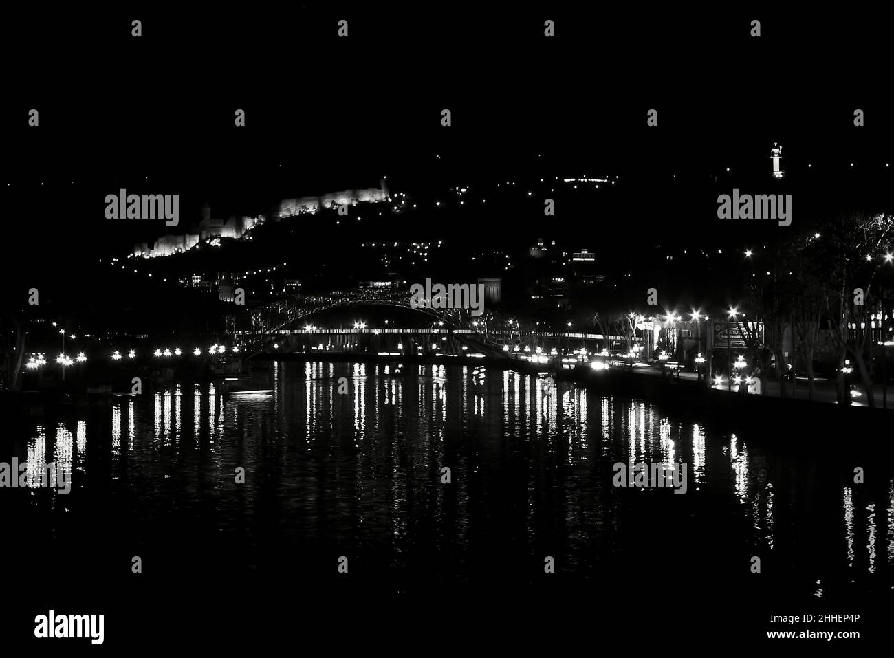 Nächtliches Stadtbild mit hellen Lichtern, die sich im Wasser spiegeln. Schwarz-weißes Stadtbild. Stockfoto