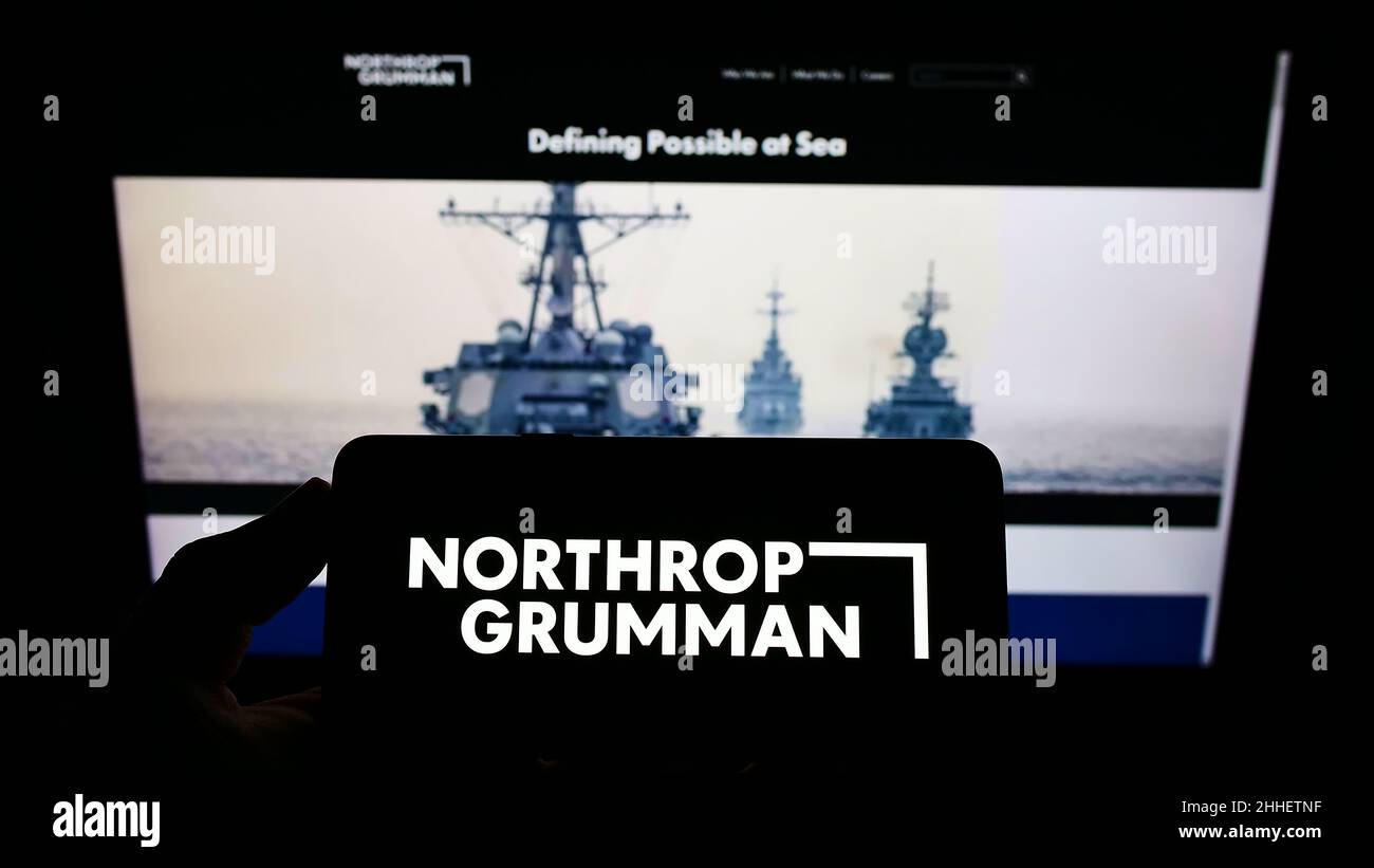 Person, die das Smartphone mit dem Logo des US-Verteidigungsunternehmens Northrop Grumman Corporation auf dem Bildschirm vor der Website hält. Konzentrieren Sie sich auf die Telefonanzeige. Stockfoto