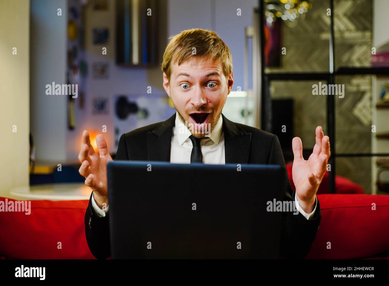 Überrascht glücklicher Geschäftsmann in schwarzem Anzug mit Laptop überrascht mit offenem Mund für Überraschung. Stockfoto
