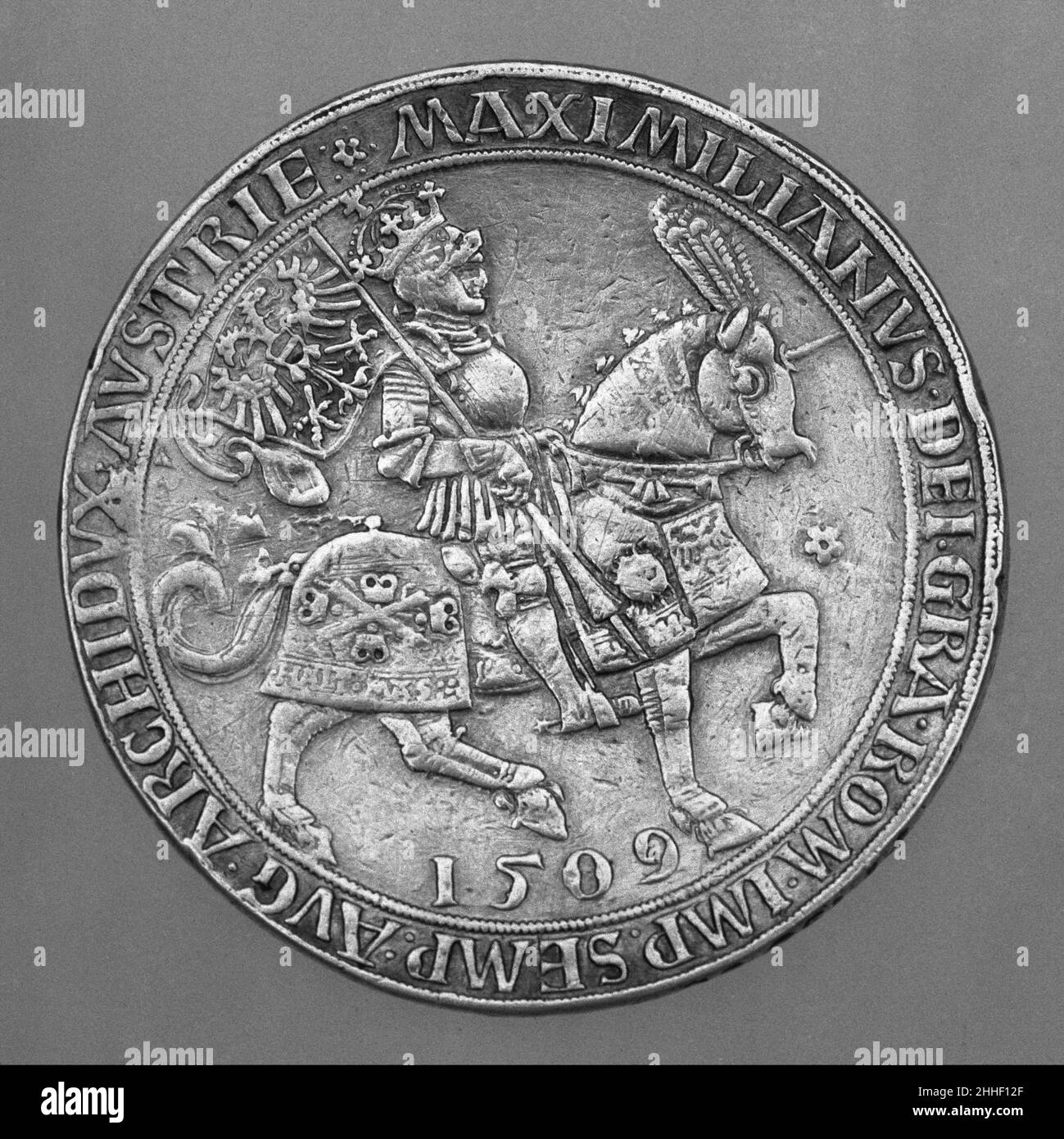 Prägemünze Maximilians I. Prägung, 1517; Stanzformen geschnitten und datiert, 1509 Ulrich Ursentaler Österreichische Prägemünzen wurden in der Regel von Hofkünstlern entworfen und von Fürsten als Belohnung oder politisches Geschenk überreicht oder als Propaganda verbreitet. Diese Münze wurde zum Gedenken an die Krönung Maximilians I. (1459–1519) zum Heiligen Römischen Kaiser im Jahr 1508 geprägt und bestärkte die dynastischen Machtansprüche des Kaiser durch Heraldik, Inschriften und seine Darstellung in voller Rüstung auf einem voll entblößten Pferd, alle Elemente aufwändig verziert. Der Barde ist von einem Typ, der eine Erfindung und eine Art von Spee zu sein scheint Stockfoto