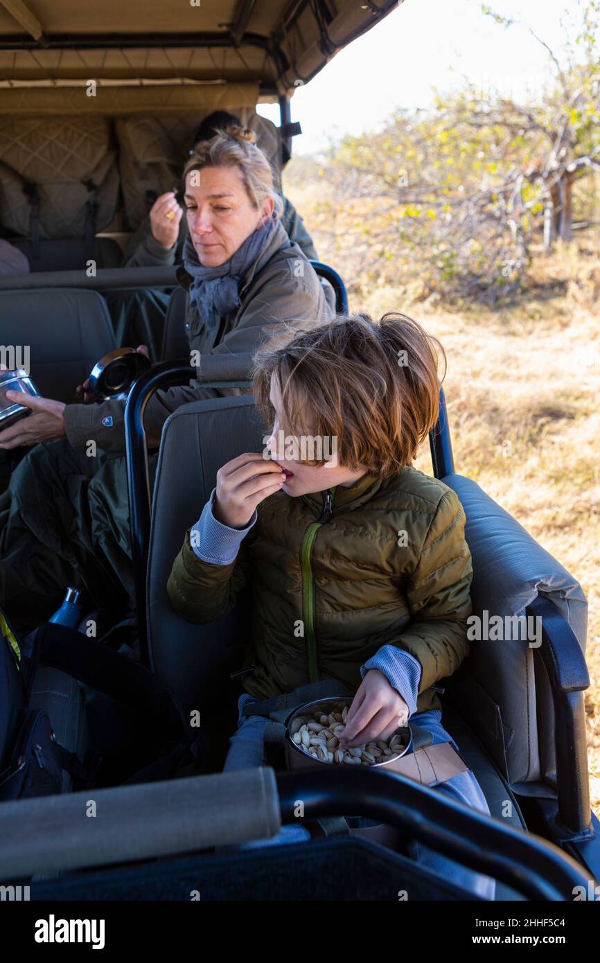 Kleiner Junge, der in einem Safarikfahrzeug sitzt und einen Snack isst. Stockfoto