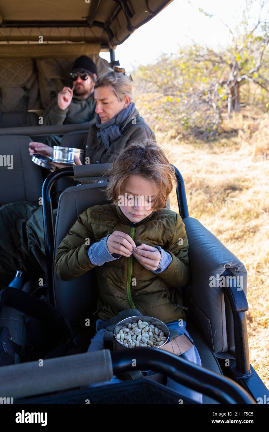Kleiner Junge, der in einem Safarikfahrzeug sitzt und einen Snack isst. Stockfoto
