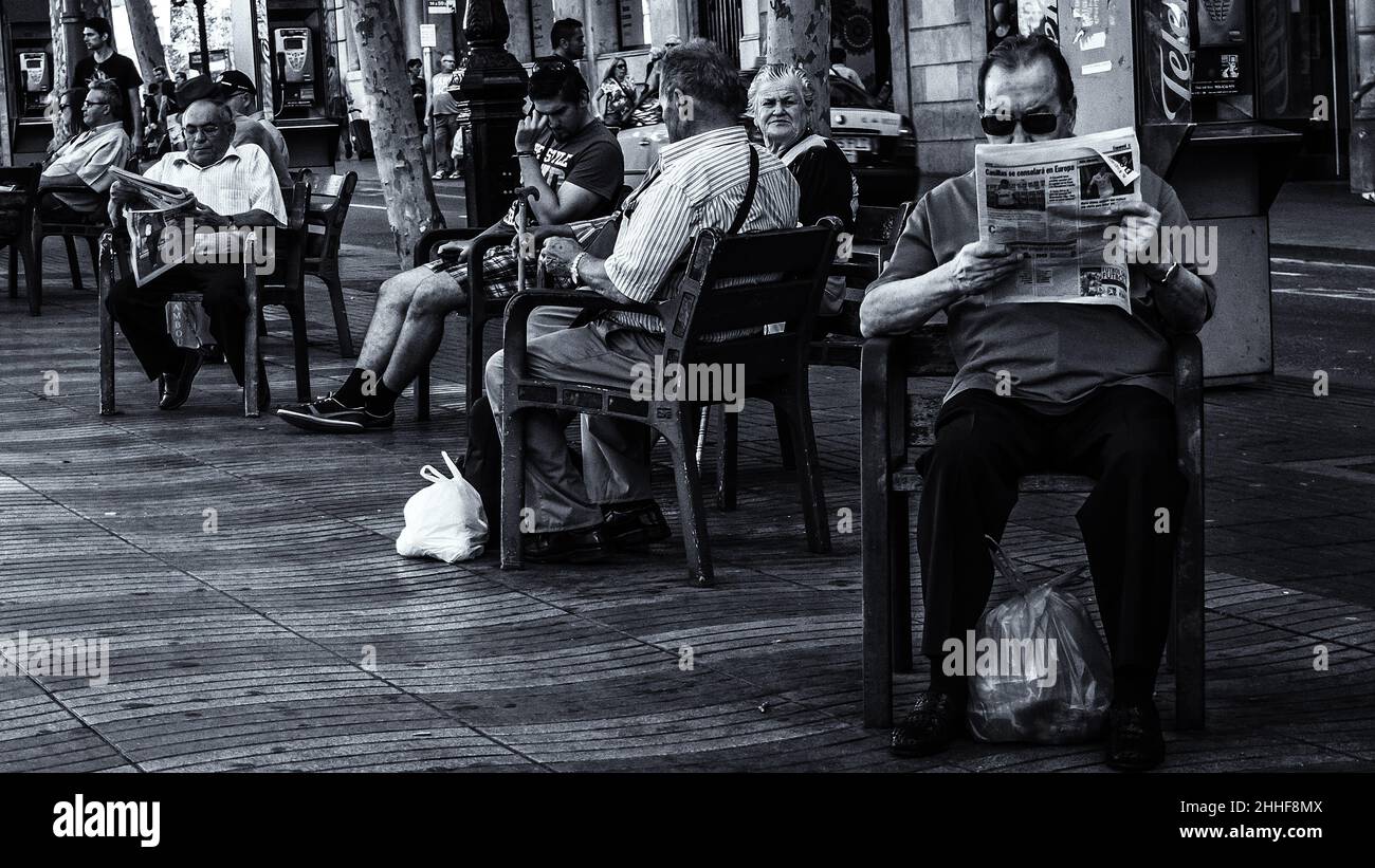 Auf der La Rambla sitzt eine Gruppe von Einheimischen, die in der Tageszeitung lesen Stockfoto