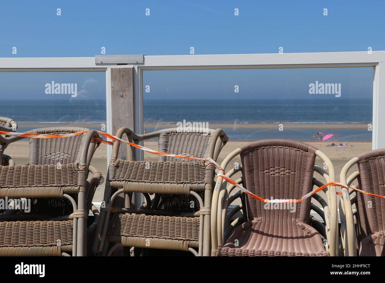 Gestapelte Stühle auf geschlossenem Strandrestaurant am sonnigen Sommertag in Zandvoort, Niederlande Stockfoto