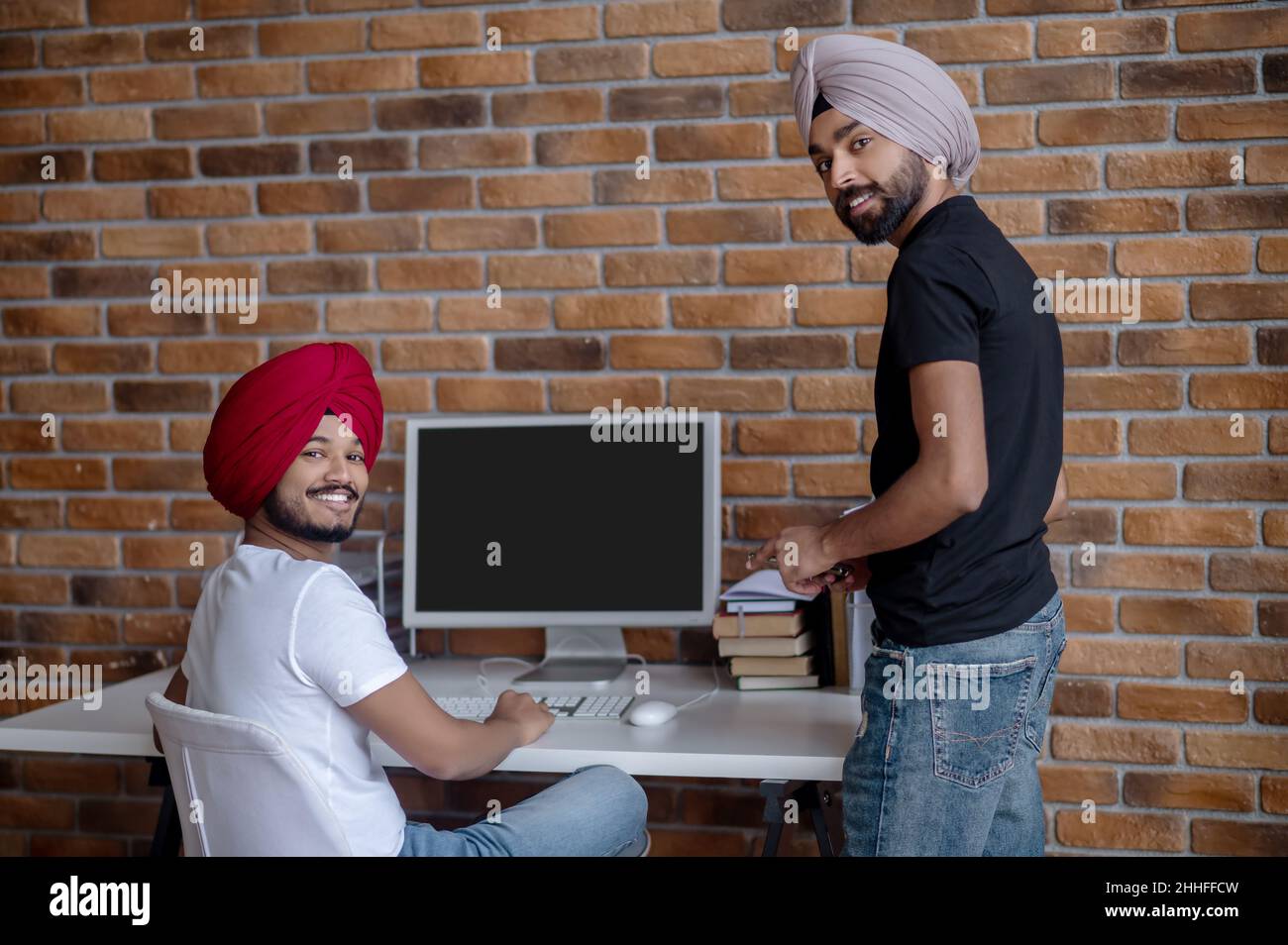 Zwei indische Männer arbeiten zusammen und sehen zufrieden aus Stockfoto