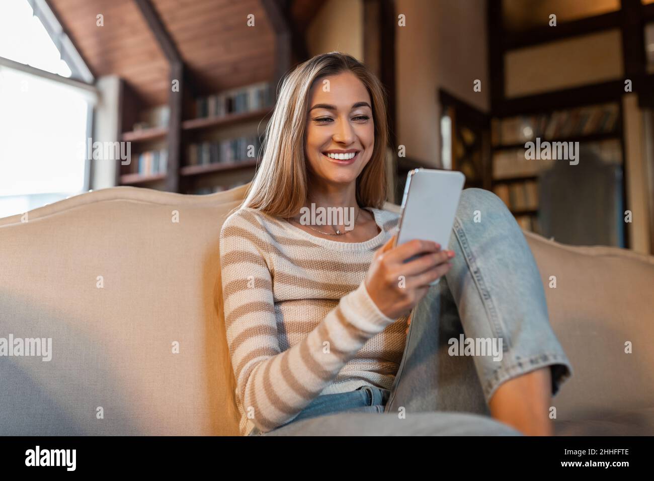 Porträt einer lächelnden Frau, die zu Hause das Smartphone benutzt Stockfoto