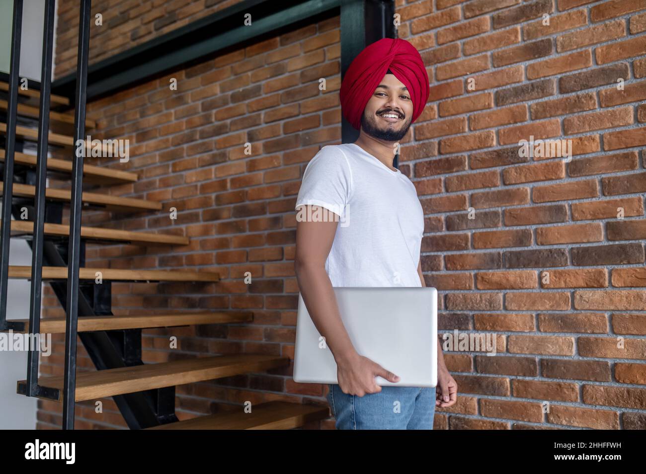 Junger inder im roten Turban, der auf Treppen steht Stockfoto
