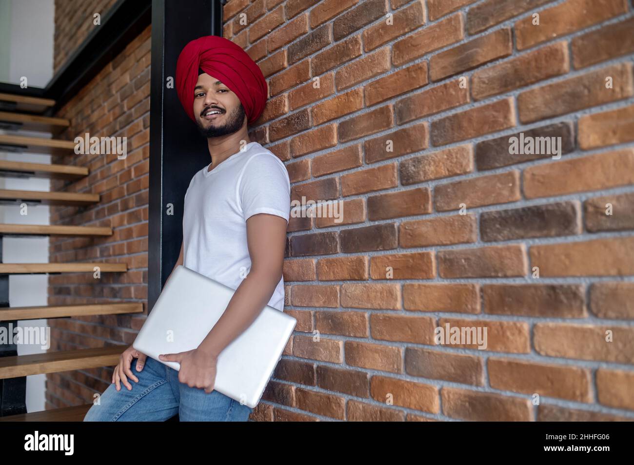 Junger inder im roten Turban, der auf Treppen steht Stockfoto