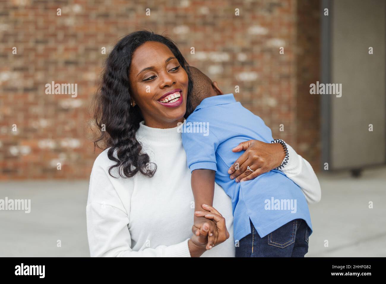 Eine schöne afroamerikanische Mutter, die ihren Kleinkind umarmt Stockfoto