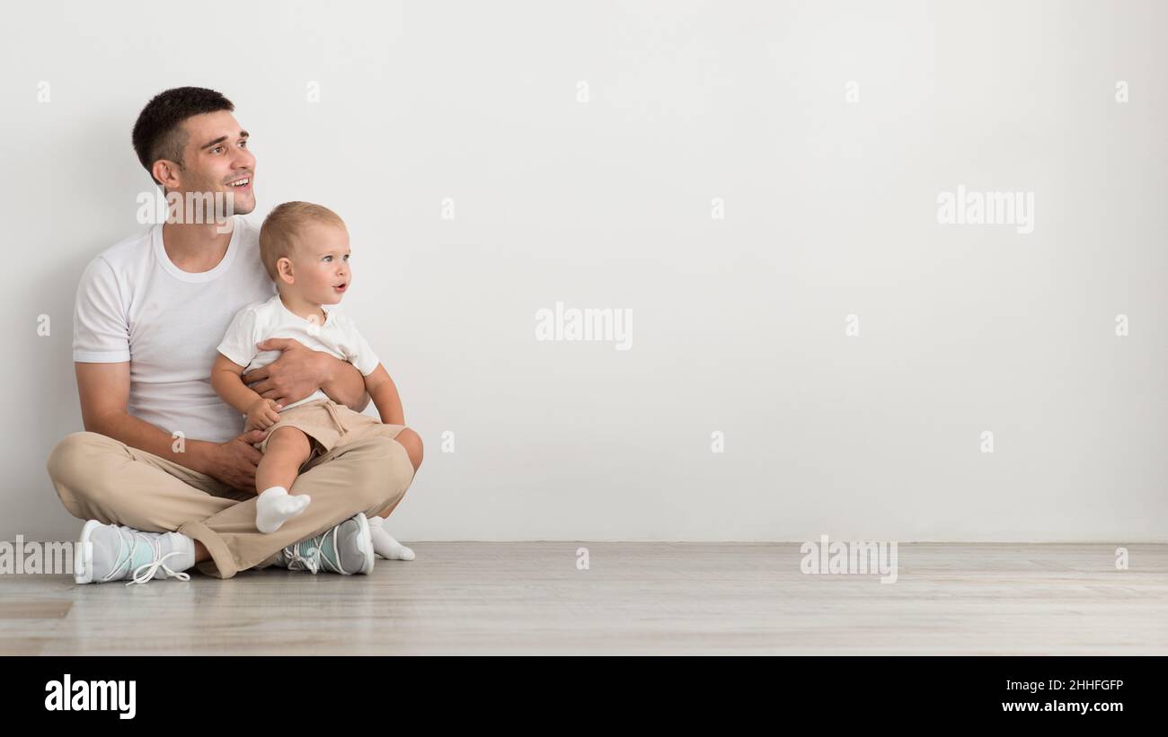 Babyangebot. Vater Mit Kleinkind Auf Den Armen Schaut Mit Interesse Beiseite Stockfoto