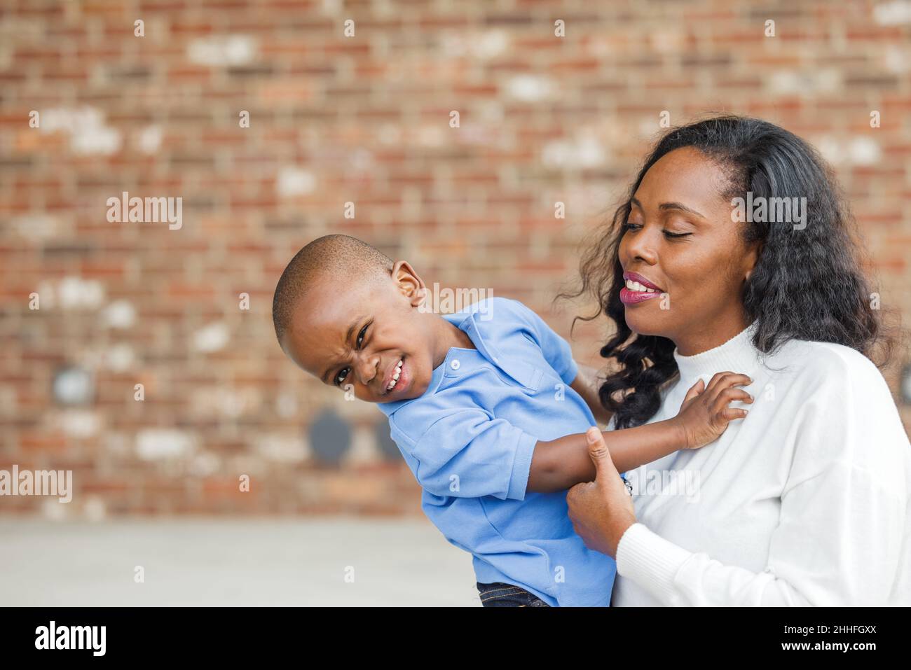 Eine wunderschöne afroamerikanische Mutter, die ihren Sohn im Vorschulalter umarmt Stockfoto
