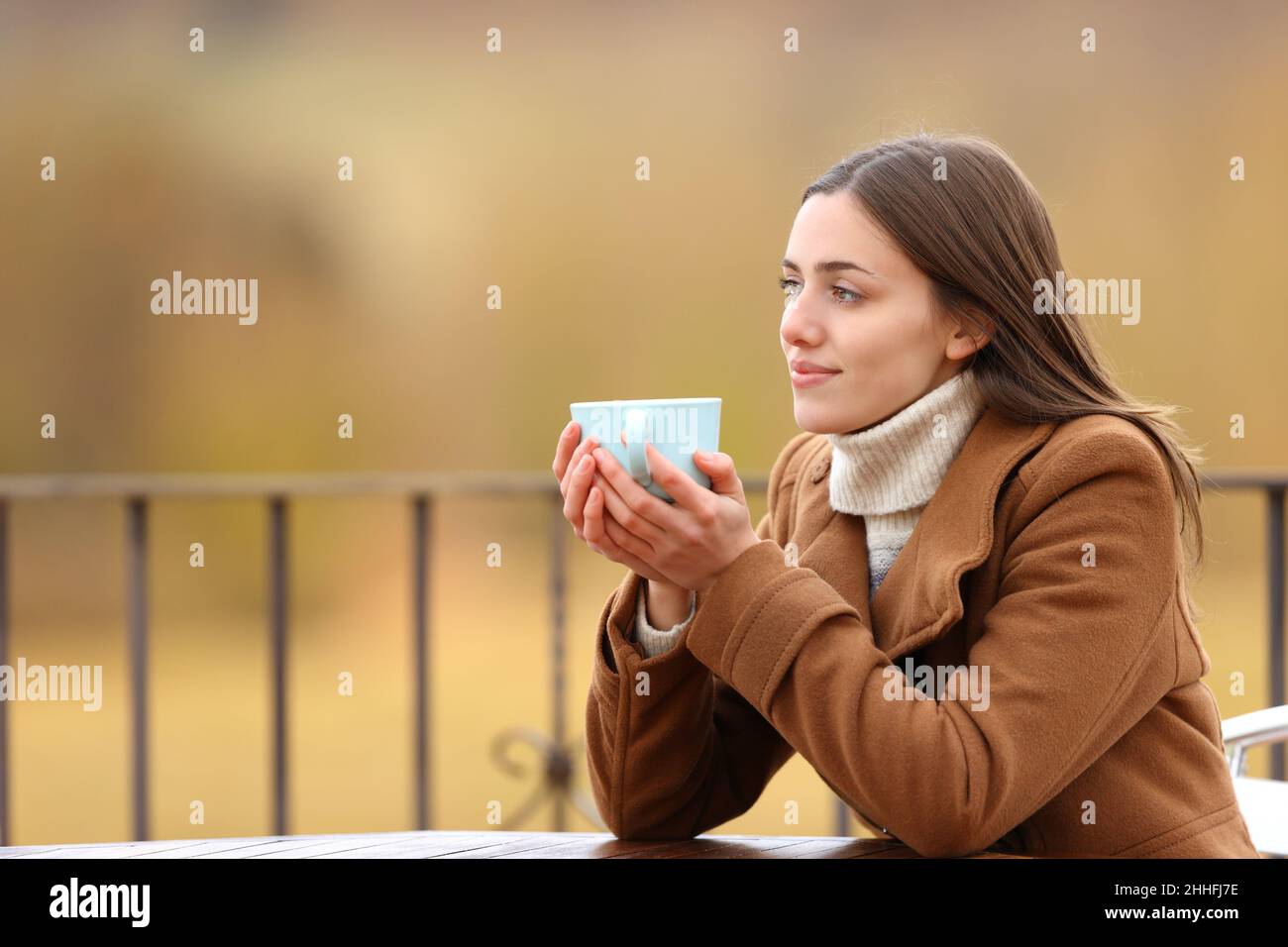 Entspannte Frau, die im Winter auf einer Terrasse Kaffee trinken kann Stockfoto