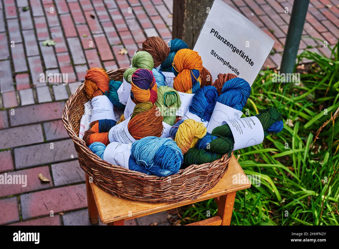 Verschiedene Skeins aus bunt gefärbter Wolle in einem Korb vor einem Laden. Stockfoto