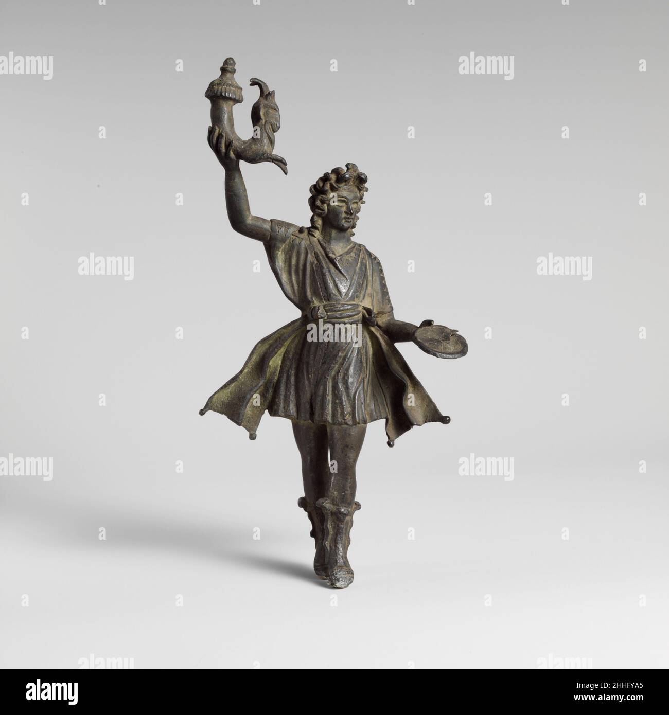 Bronzestatuette eines Lar 1st–2nd Jahrhundert n. Chr. Roman die Lar familiaris war eine Haushaltsgottheit, die die Mitglieder der Familie schützte und ihre Gesundheit und ihren Wohlstand sicherte. Ab der Zeit des Augustus enthielt das Lararium (ein kleiner Schrein, der in jedem römischen Haus gefunden wurde) zwei lares, die jeweils die gleichen Attribute wie ein Rhyton (Trinkgefäß) und eine Patera (Opferschale) hatten. Bronzestatuette eines Lar. Roman. 1st–2nd Jahrhundert n. Chr. Bronze. Britisch. Bronzen Stockfoto