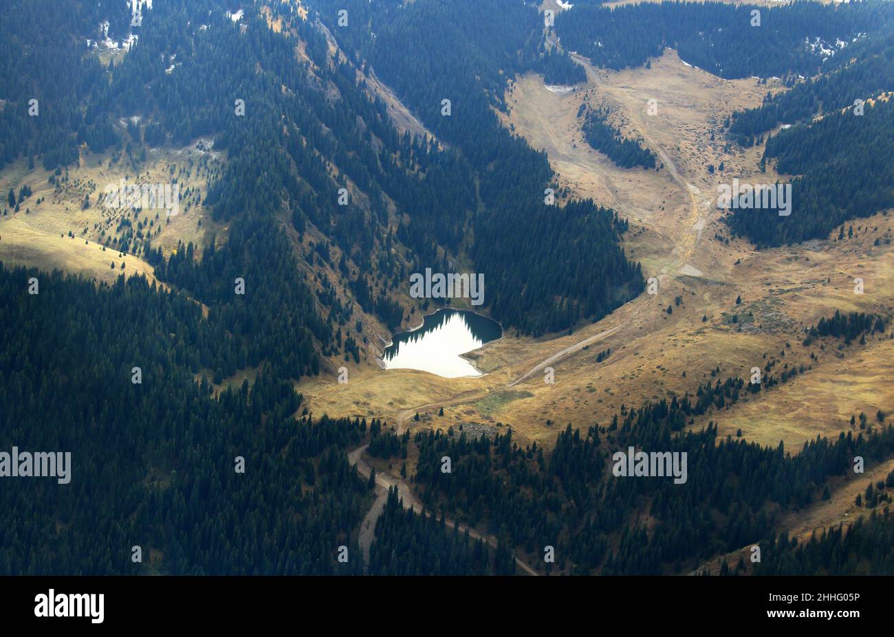 Draufsicht auf einen See, umgeben von Wald hoch in den Bergen im Herbst, Luftaufnahme Stockfoto