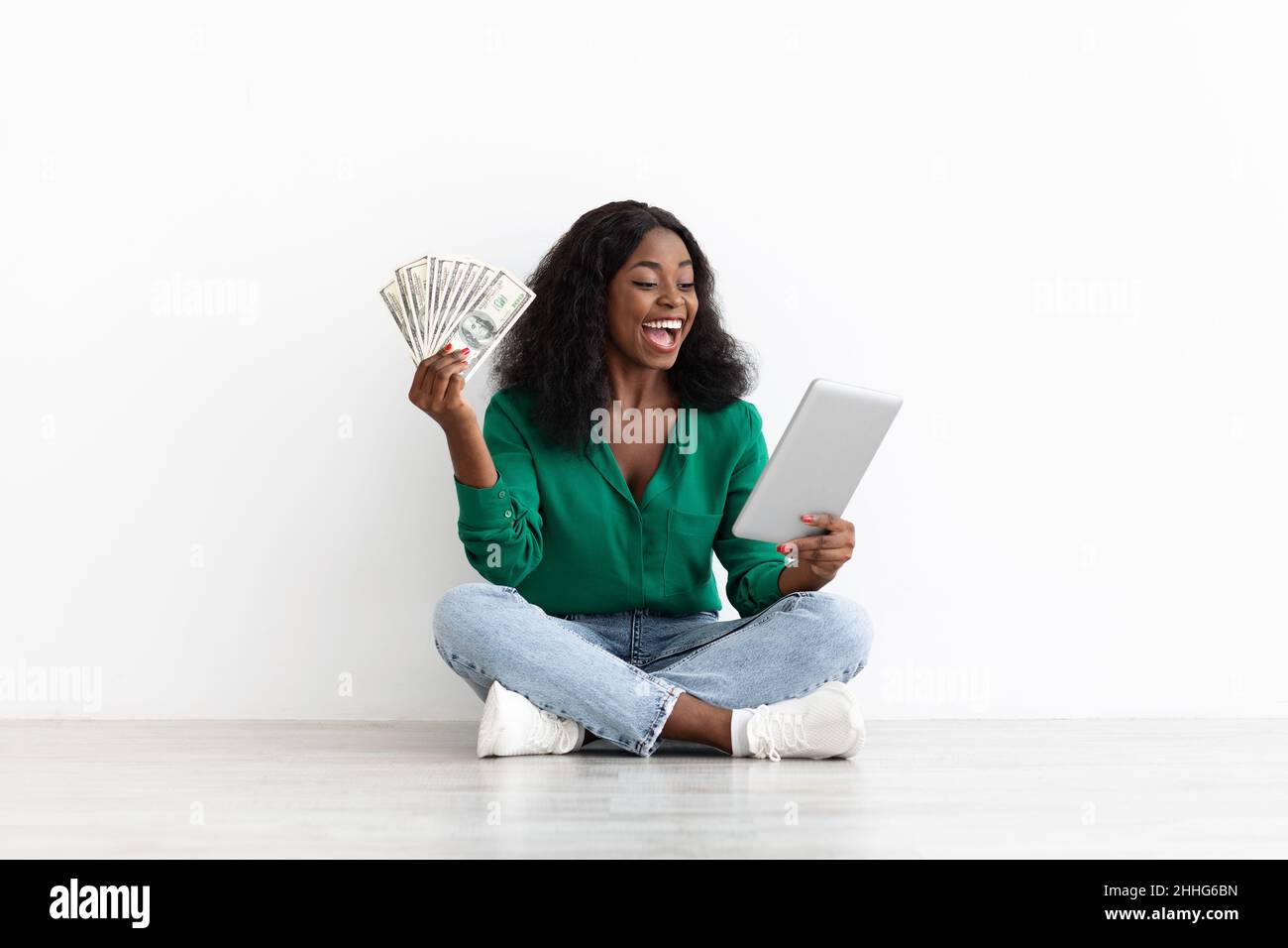 Glückliche schwarze Dame mit digitalem Tablet und Bargeld auf Weiß Stockfoto