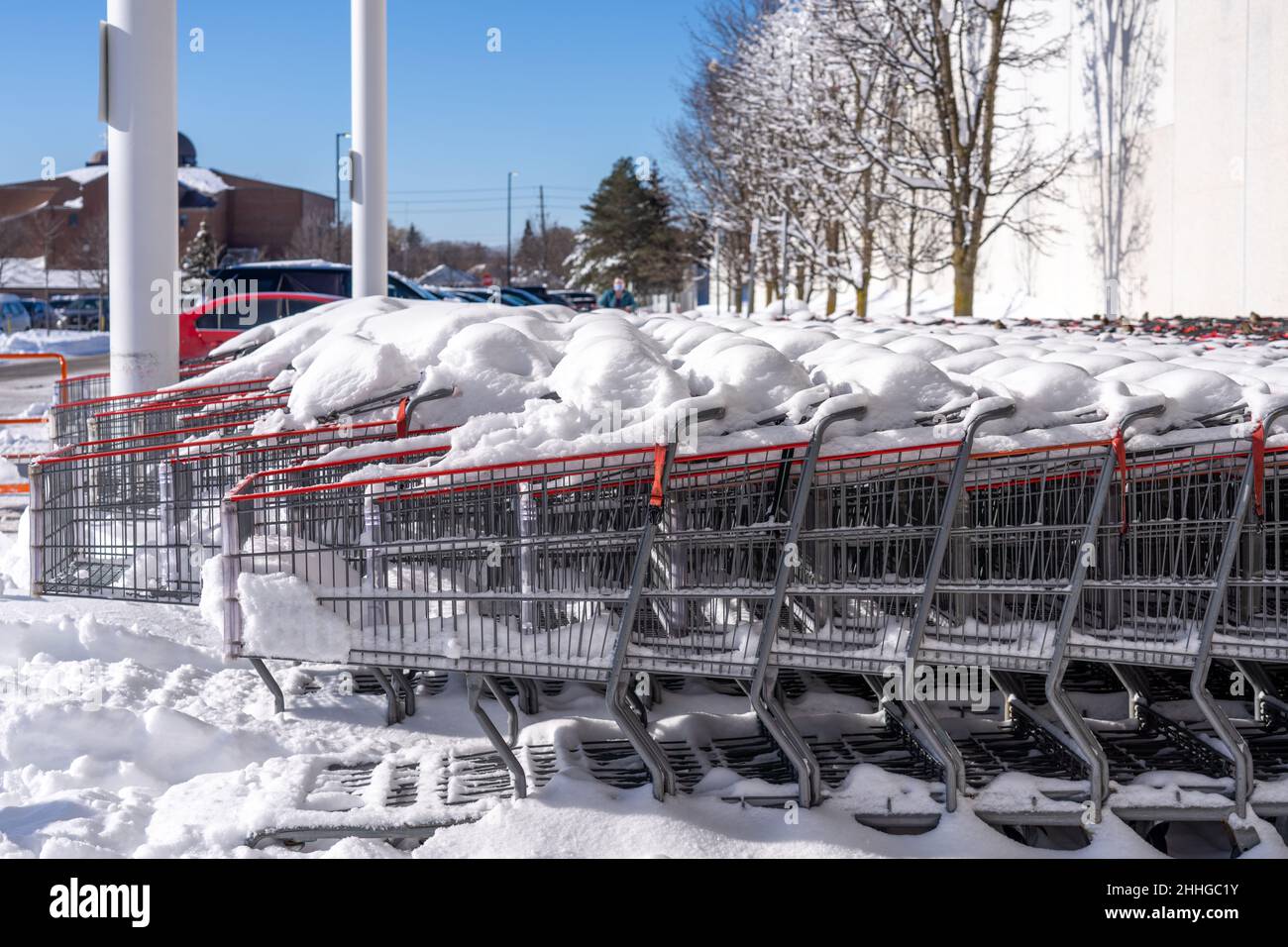 Große Gruppe von Einkaufswagen mit Schnee bedeckt vor einem Supermarkt während der Wintersaison in der Stadt. Stockfoto