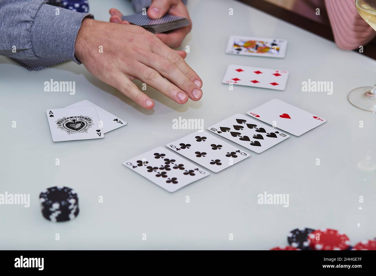 Die Hände des Mannes mischen Karten. 2 Asse auf dem Tisch in einem Pokerspiel mit Chips, Karten auf dem Tisch. Genießen Sie den Moment, digitale Entgiftung mit Freunden. Lifestyle-Fotografie. Ehrliche Momente. Selektiver Fokus Stockfoto
