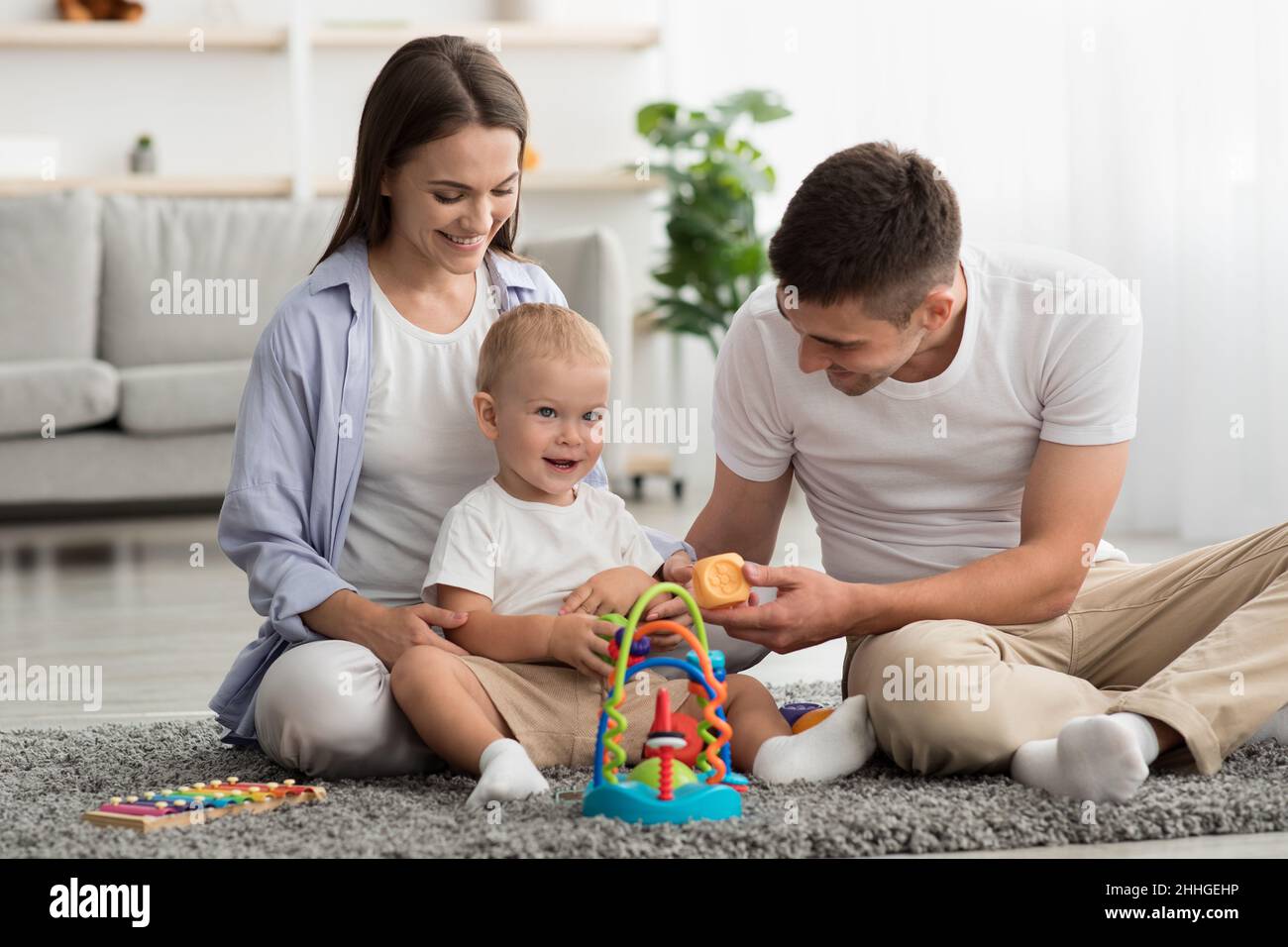 Glückliche Eltern Und Entzückendes Kleinkind Baby Spielen Mit Entwicklung Spielzeug Zu Hause Stockfoto