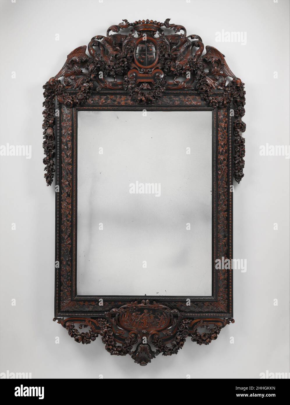 Spiegel ca. 1685–1700 Johannes Hannart (oder Jan Hanat) Dieser Rahmen, Der zusammen mit seinem Paar (Rijksmuseum, Amsterdam) Eine Tour de Force der Schnitzerkunst darstellt, wurde höchstwahrscheinlich dazu geschaffen, ein Eheportrait zu zeigen, das nicht identifizierte Wappen im Wappen, das sich auf den Sitter bezieht. Mit Ebenholz furniert, mit fein geschnitzten Buchsbaumstücken und Girlanden aus naturalistischen Blumen verziert, ist der Rahmen von Hannart, der in Den Haag und Leyden tätig war, signiert. Dieser Künstler arbeitete sowohl in Holz als auch in Stein, was darauf hinweist, dass die traditionelle Trennung zwischen Steinbildhauern und Holzschnitzern nicht lange dauern konnte Stockfoto