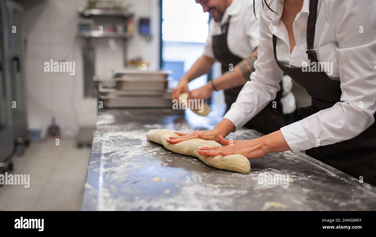 Nicht erkennbarer Koch und Koch, der in der Restaurantküche an ihren Gerichten arbeitet. Stockfoto