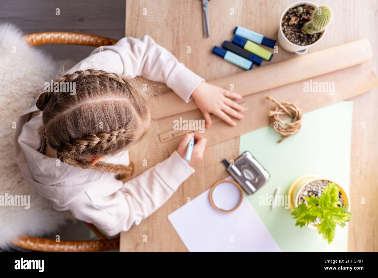 Mädchen im Prozess des Skizzierens mit Bleistift auf Bastelpapier. Draufsicht der Tabelle. Schulmädchen oder Vorschulkinder machen Hausaufgaben oder Projekte, zu Hause. Gerade Stockfoto