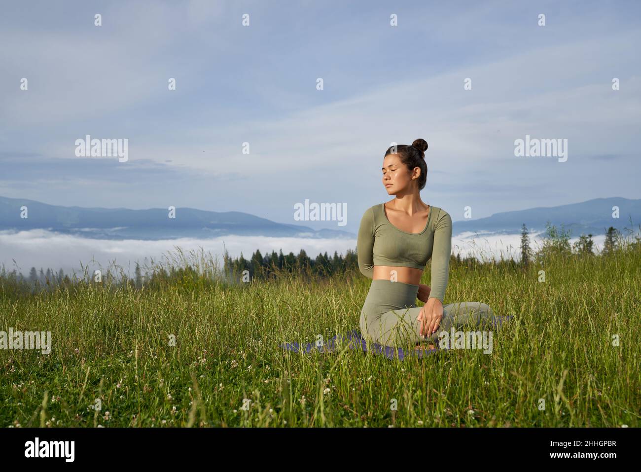 Gesunde, fit Dame in Sportkleidung sitzt auf Yoga-Matte und macht Fitness-Übungen im Freien. Konzept der Menschen, Training und gesunde Lebensweise. Stockfoto