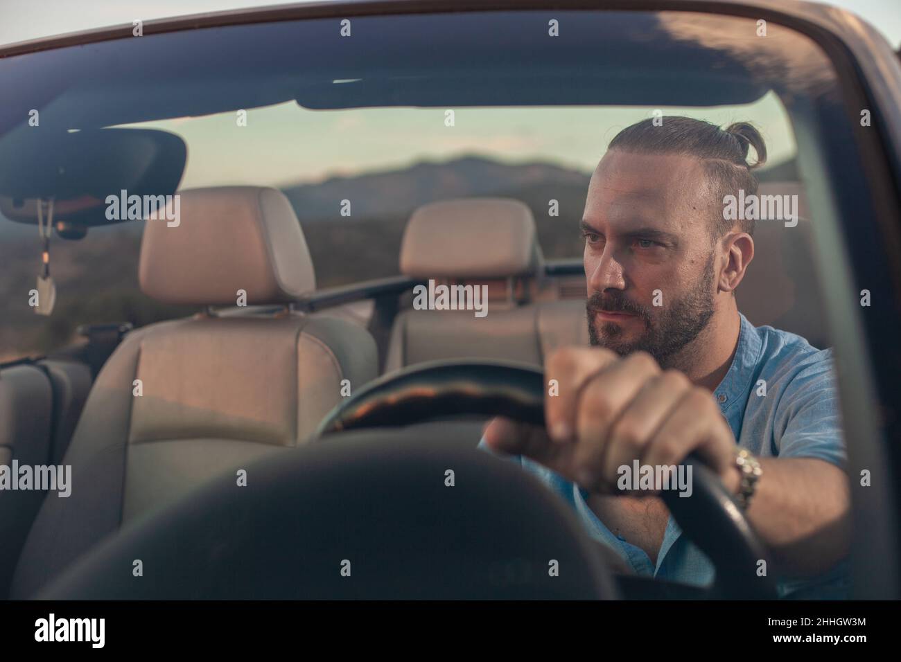 Mann fährt Cabrio Auto in der Landschaft bei Sonnenuntergang Stockfoto