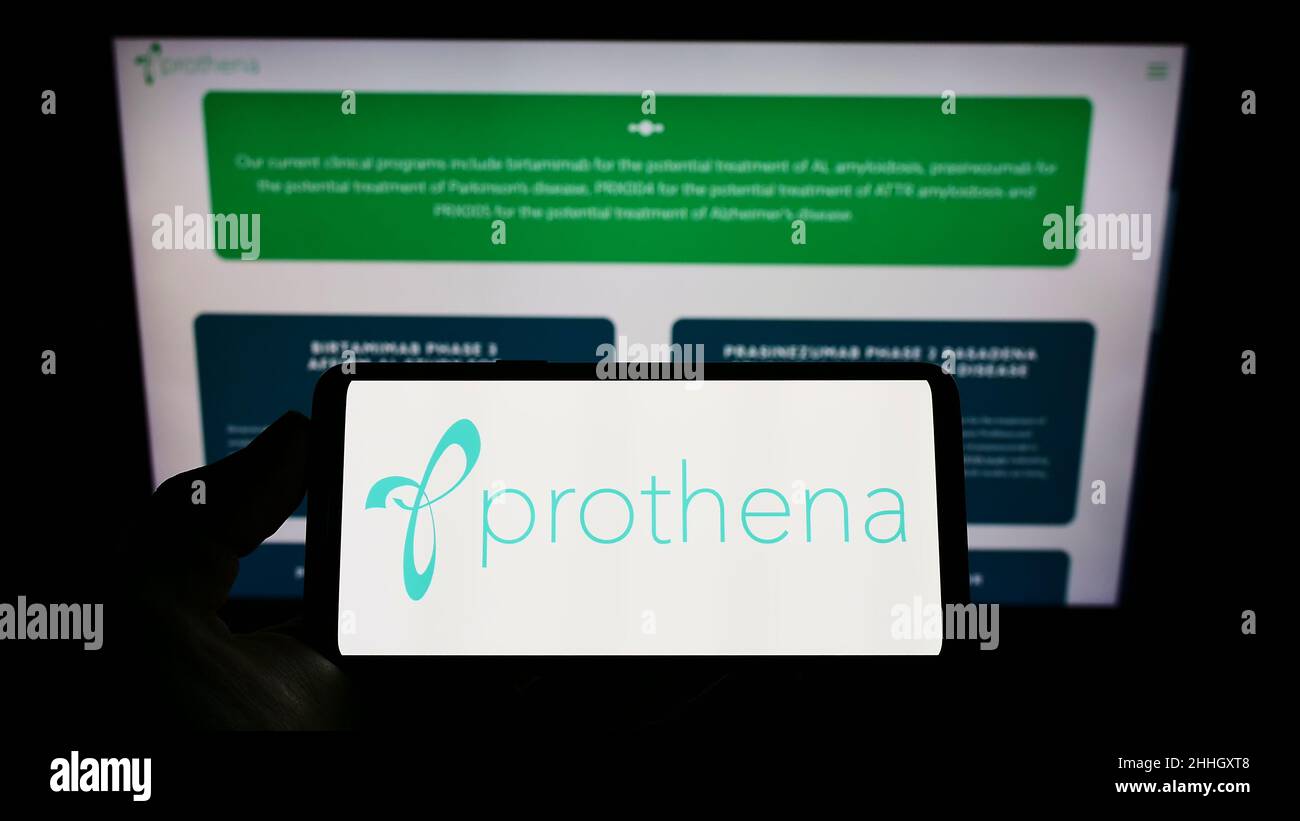 Person mit Mobiltelefon und Logo des Biotechnologie-Unternehmens Prothena Corporation plc auf dem Bildschirm vor der Webseite. Konzentrieren Sie sich auf die Telefonanzeige. Stockfoto