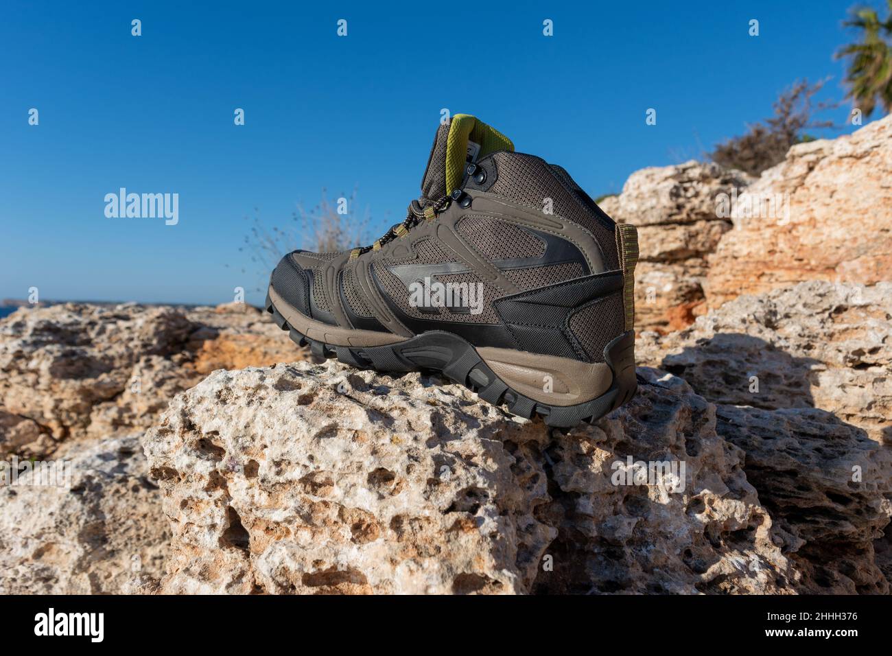 Olivgrüne Wanderschuhe auf einem natürlichen Hintergrund aus Meer und Felsen. Stockfoto