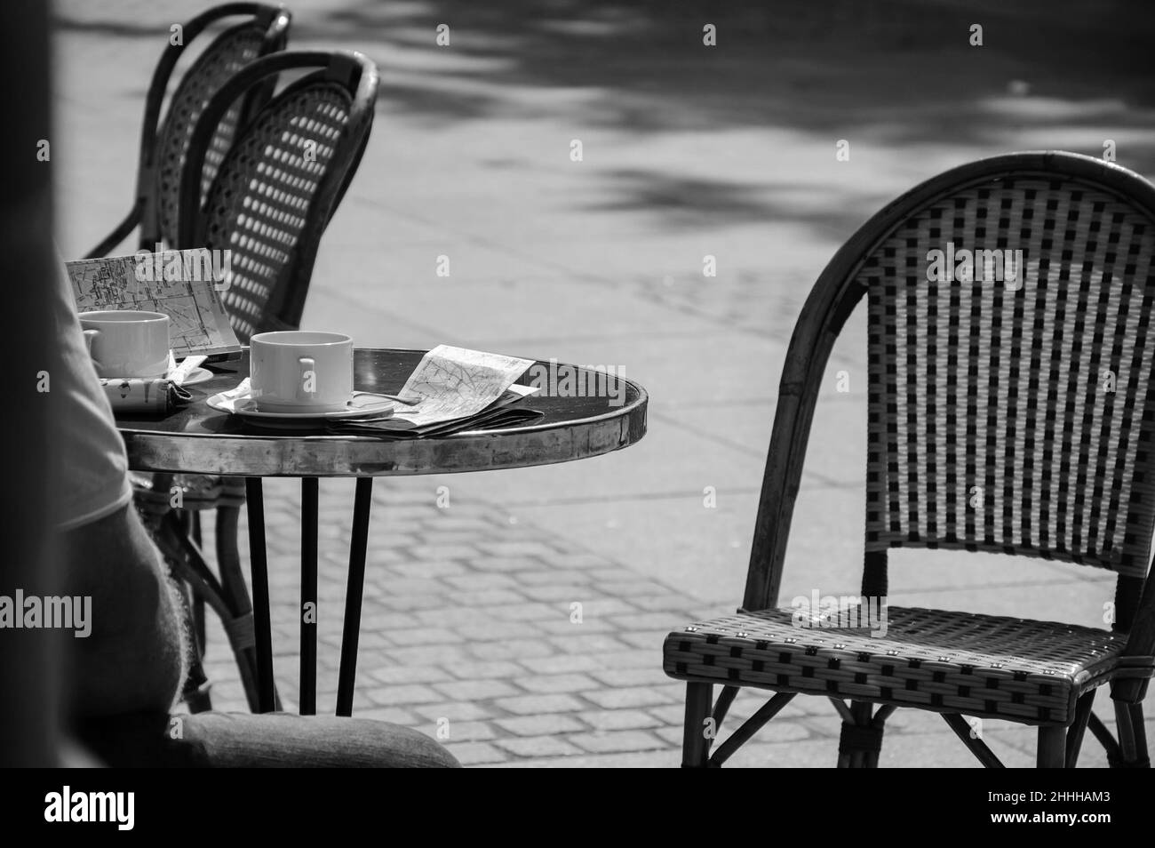 Tourist in Pariser Café mit Tasse Kaffee, Stadtführer und Karte. Historisches Foto in Schwarzweiß Stockfoto