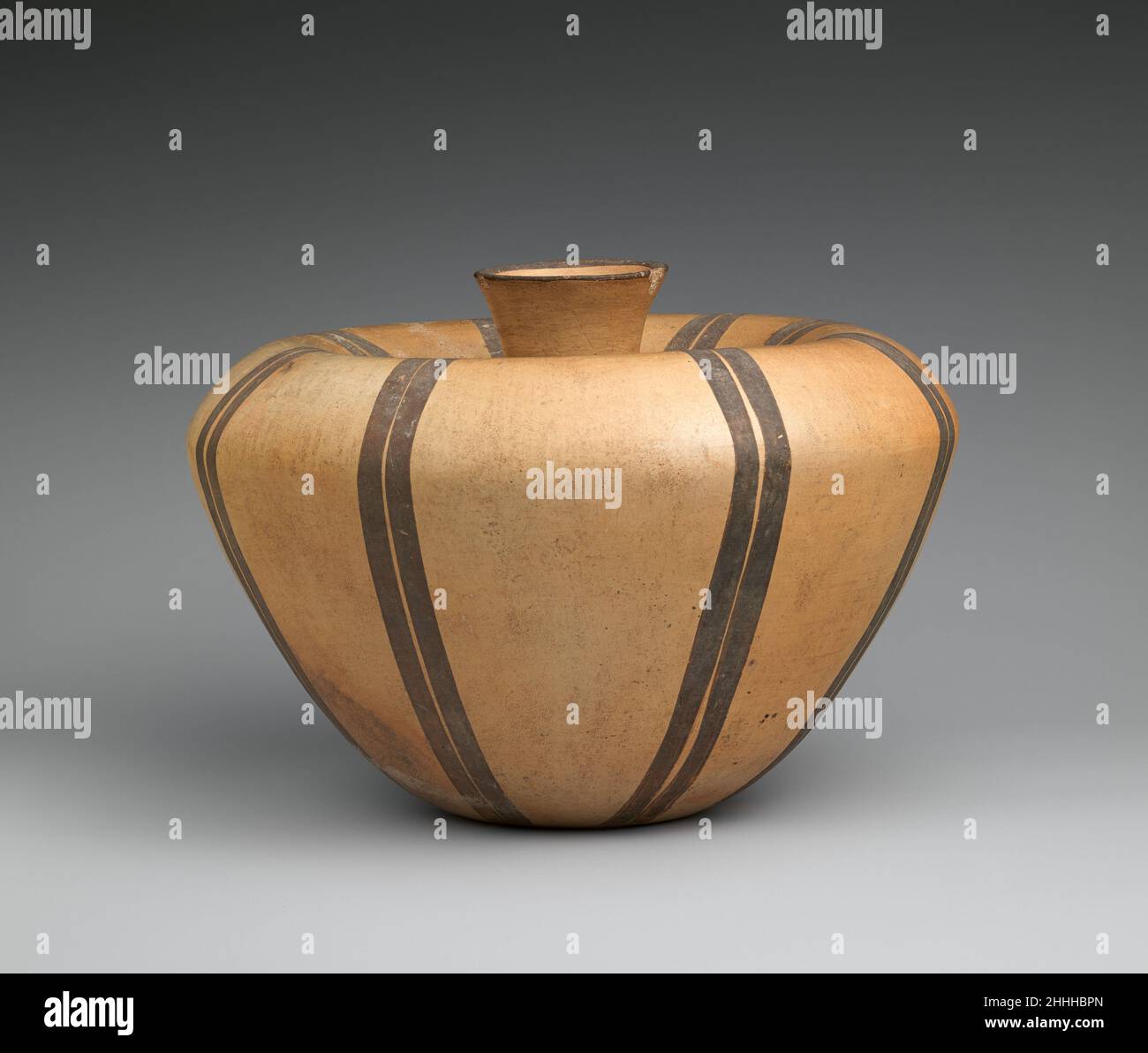 Glas 2nd–4th Century Nayarit (Chinesco) Dieses große Glas hat einen flachen Boden mit stark abfackeln Wänden, die sich an der Schulter in Richtung des in die Mitte eingelassenen Auslaufes verziehen. Die brünierte Oberfläche ist mit hellgelbem Slip bedeckt. Acht Paare von vertikalen parallelen braunen Linien teilen die Oberfläche in gerade Segmente. Glas. Nayarit (Chinesco). 2nd–4th Jahrhundert. Keramik. Mexiko, Mesoamerika, Nayarit. Keramik-Behälter Stockfoto