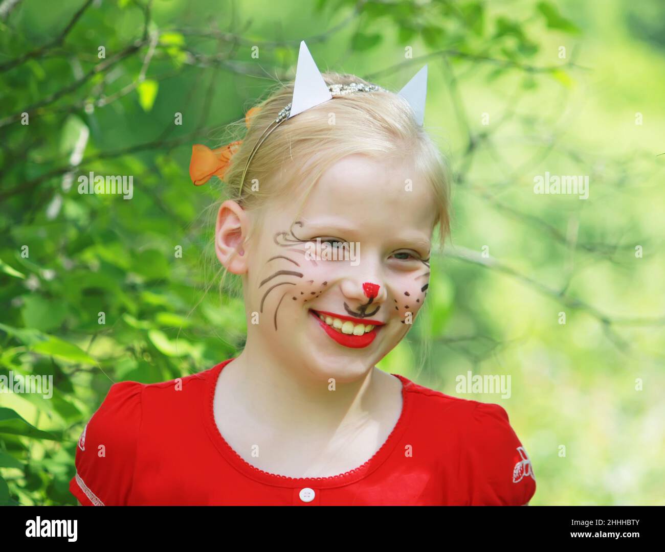 Schöne glücklich lächelnde junge blonde kaukasische Mädchen mit Gesicht gemalt wie eine Katze auf Sommer Natur Hintergrund. Stockfoto