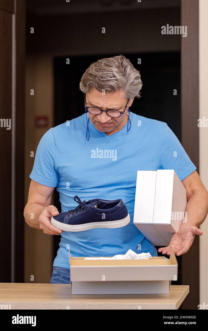 Ein Mann ist unzufrieden mit dem Kauf von Schuhen aus dem Laden. Schlechtes Produkt. Stockfoto