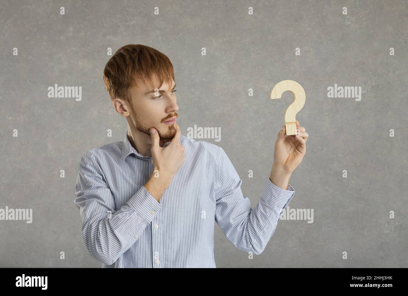 Junger hübscher kaukasischer Mann isoliert auf grauem Hintergrund mit Fragezeichen-Symbol Stockfoto