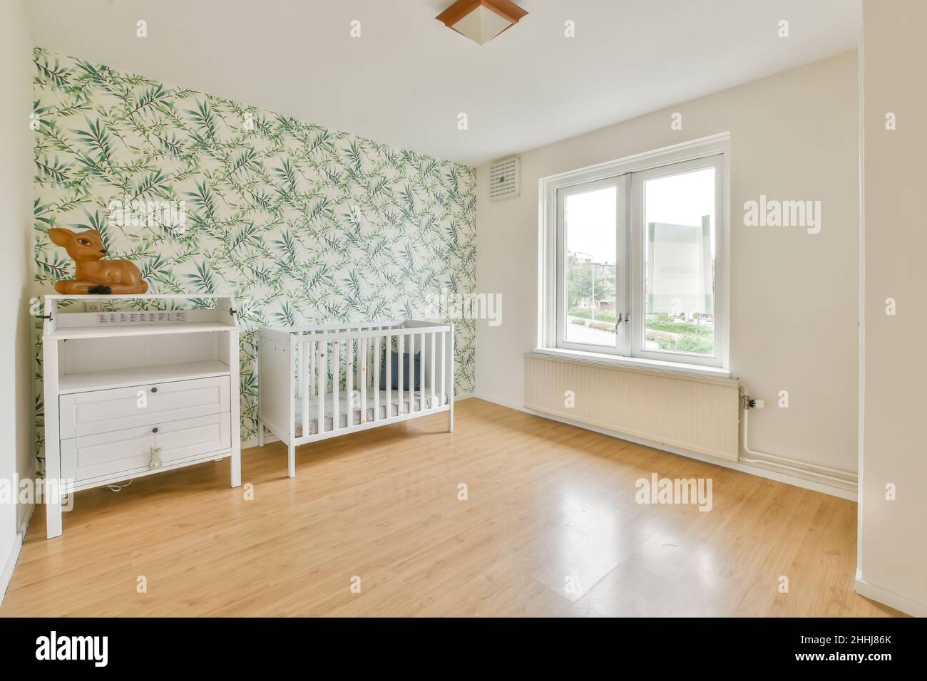 Babyzimmer mit einem weißen Kinderbett und einem weißen Schrank Stockfoto