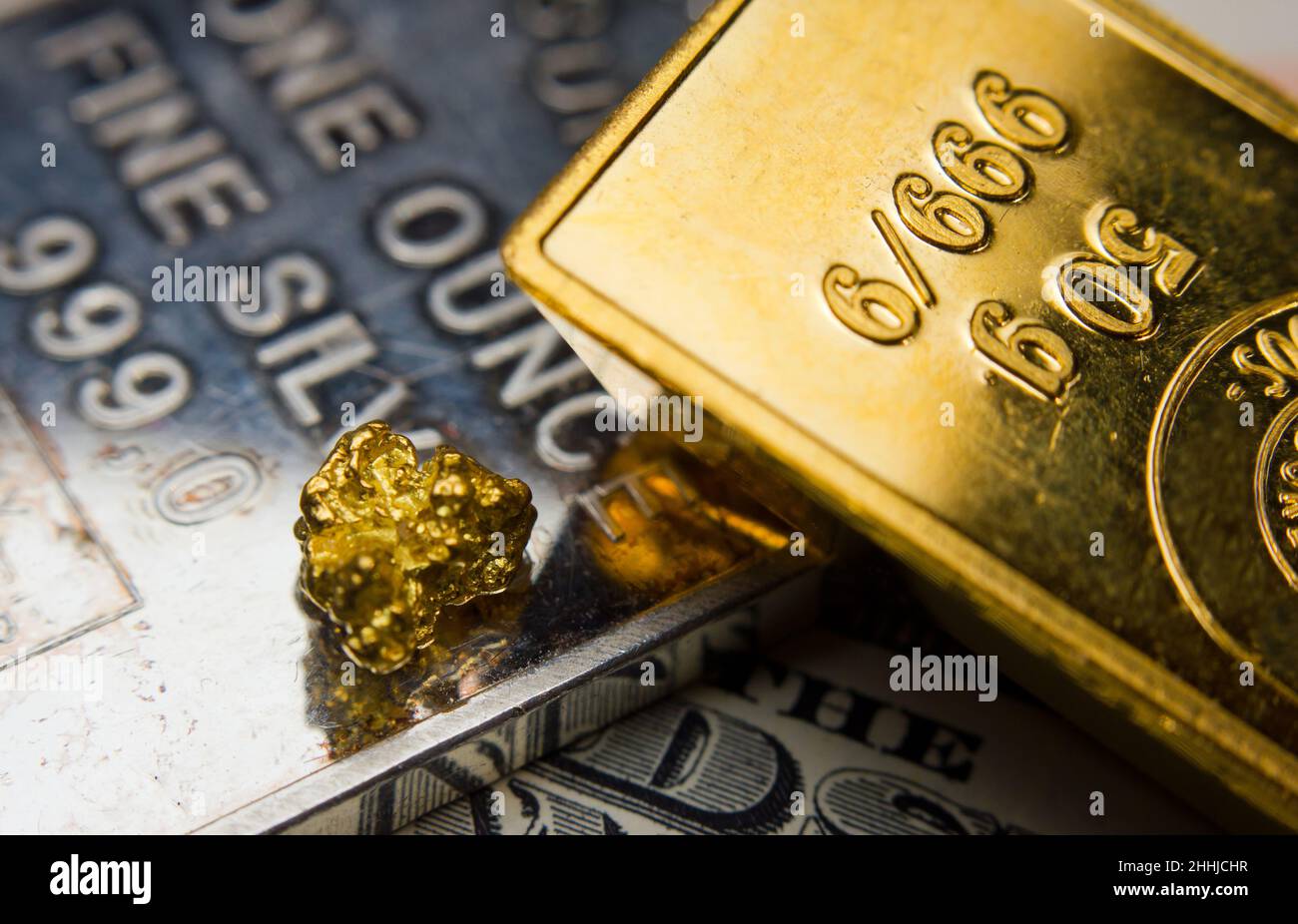 Nahaufnahme eines Goldbarren auf einer Feinunze Silber und Münze Stockfoto