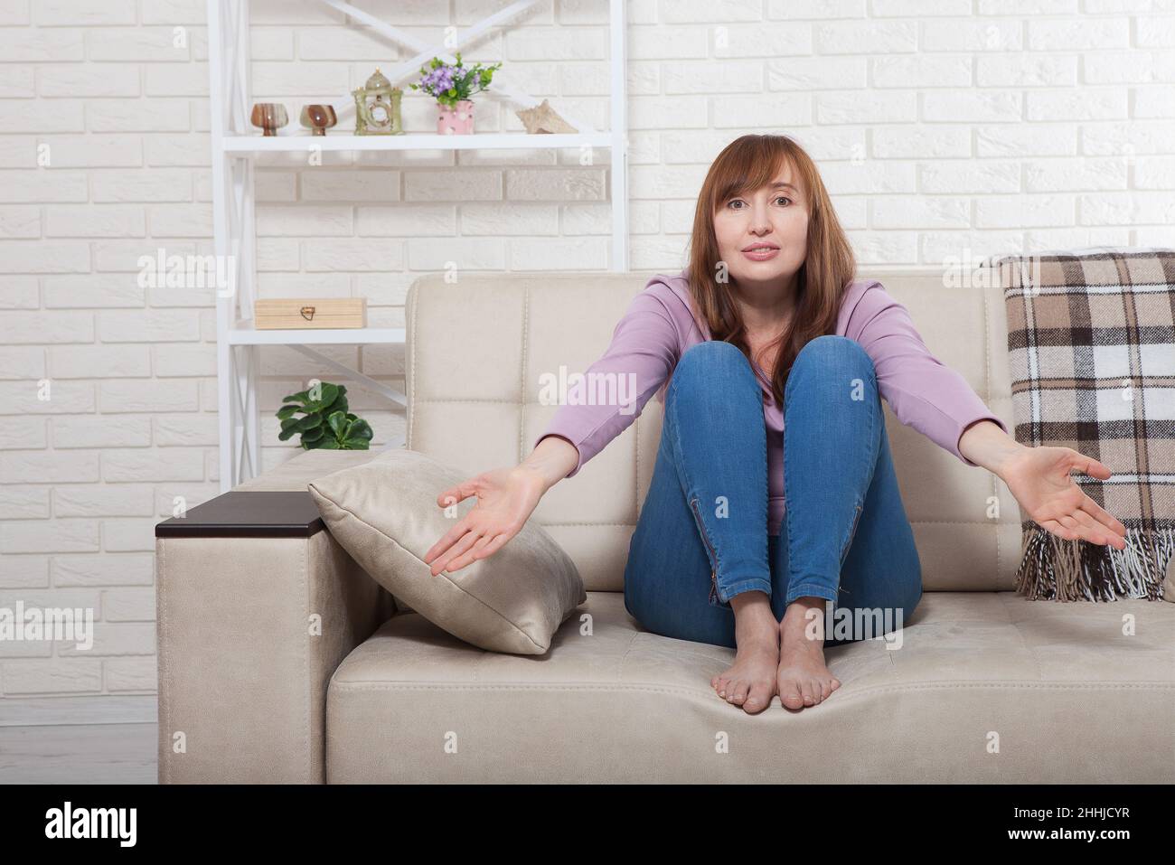 Im mittleren Alter schöne Brünette Frau verwirrt zu Hause Hintergrund. Wechseljahre Stockfoto