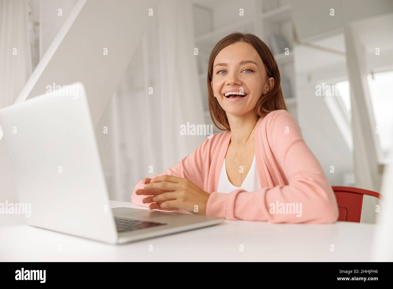 Lächelnde Dame, die Zeit zu Hause verbringt, während sie an einem Laptop arbeitet Stockfoto