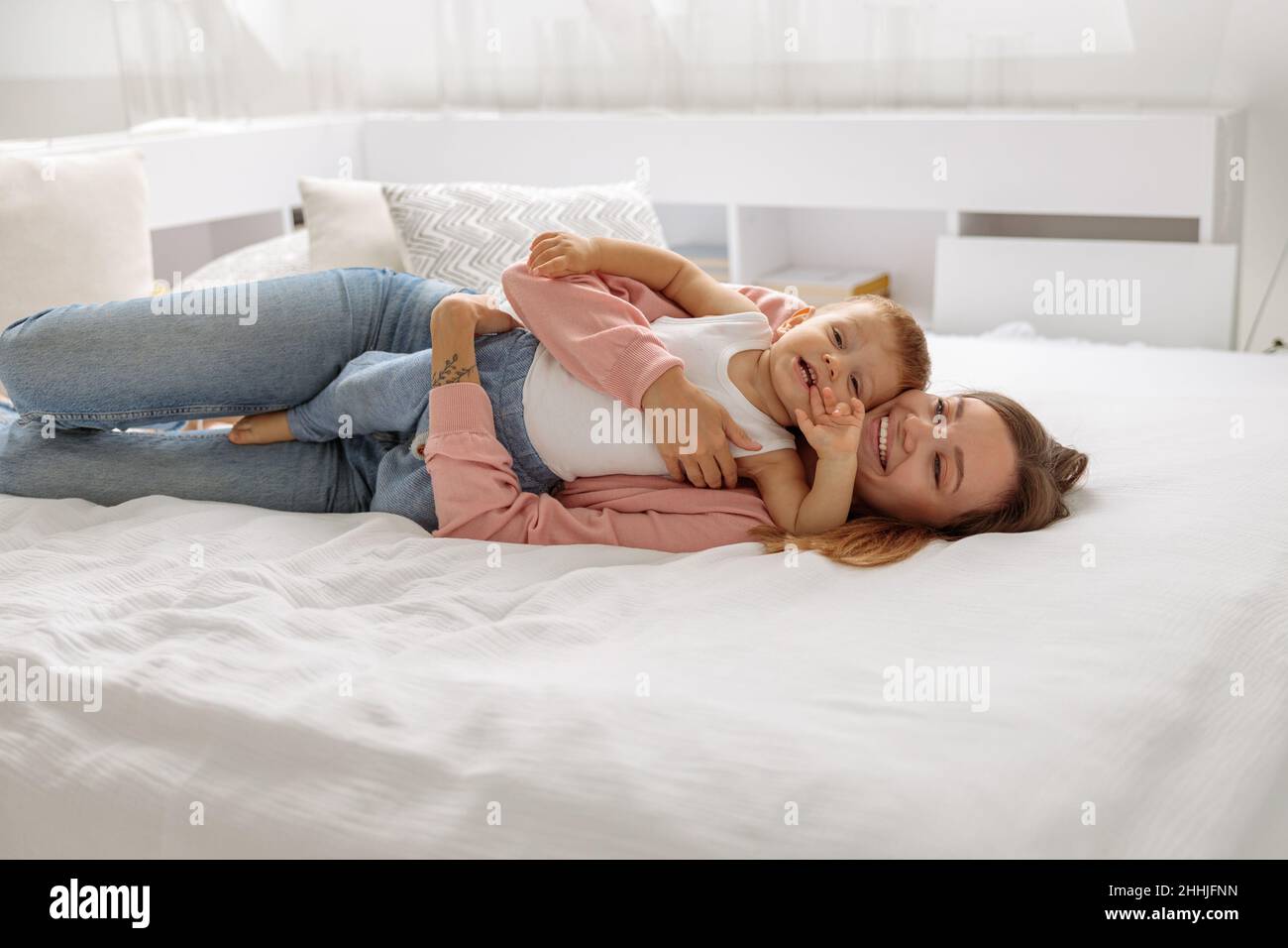 Lächelnde Dame umarmte ihren kleinen Sohn im Schlafzimmer Stockfoto